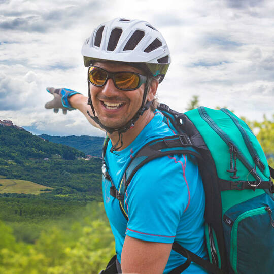 Mann fährt mit Fahrrad durch Slowenien und zeigt auf Landschaft