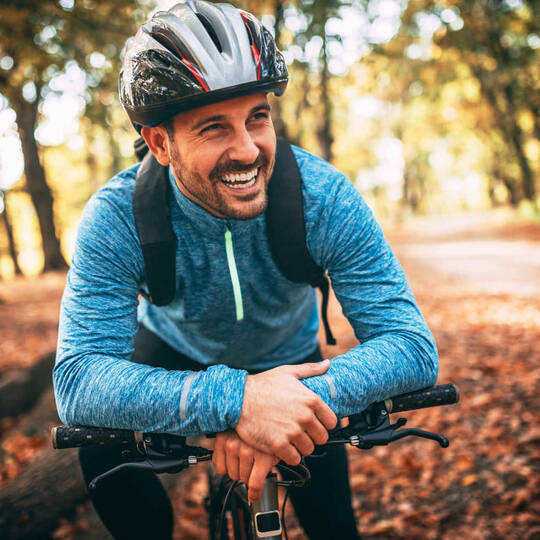 Mann mit Fahrrad und Helm mit herbstlichem Hintergrund