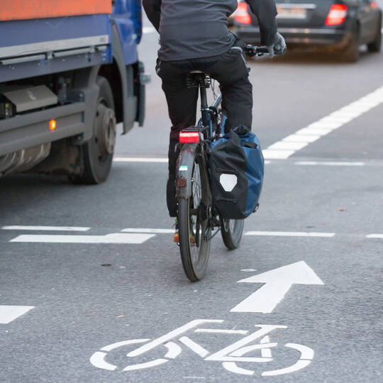 Fahrradfahrer fährt mit eingeschaltetem Rücklicht durch Straßenverkehr