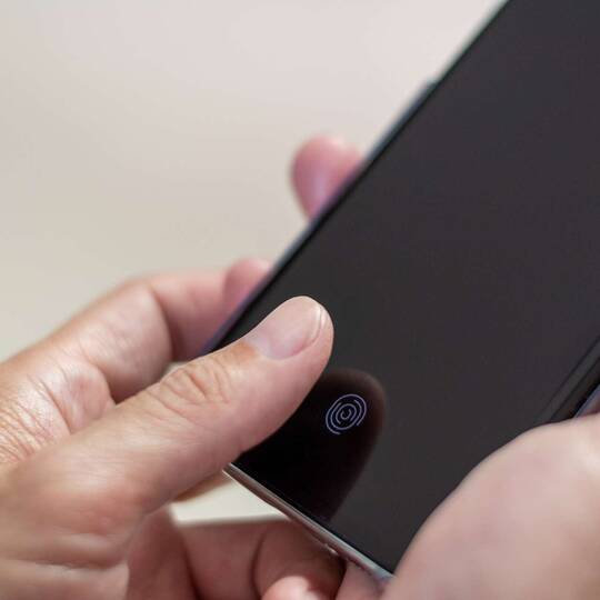 Person legt Daumen auf den Touch-ID-Sensor seines Smartphones mit Hülle