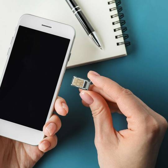 Person legt SIM-Karte in Smartphone ein