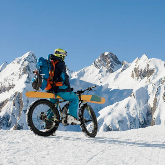 Ein E-Bike Fahrer fährt im Schnee mit seinen Skiern