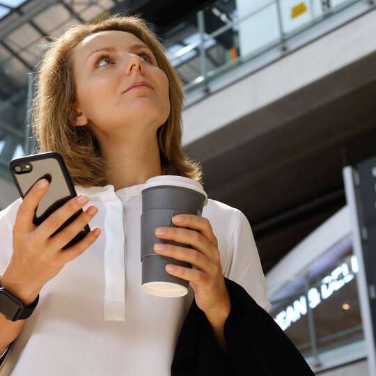 Frau am Flughafen mit Smartphone in der Hand