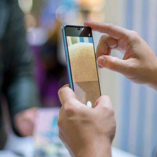 Eine  Person macht ein Foto mit einem Huawei P30 Pro. Im Hintergrund ist eine weitere Person erkennbar.