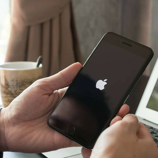 Person hält iPhone mit Apple Logo auf dem Display