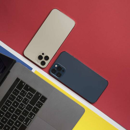 MacBook mit iPhone daneben auf rotem Untergrund