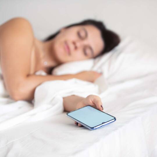 Schlafende Frau hält Smartphone in der Hand