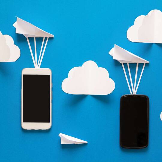 Zwei Smartphones und gefaltete Papierflugzeuge