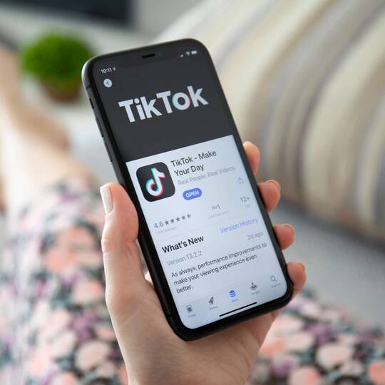 Hand hält Smartphone mit TikTok Anzeige auf dem Display
