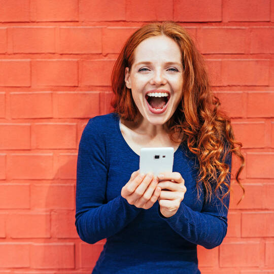 Frau freut sich am Handy