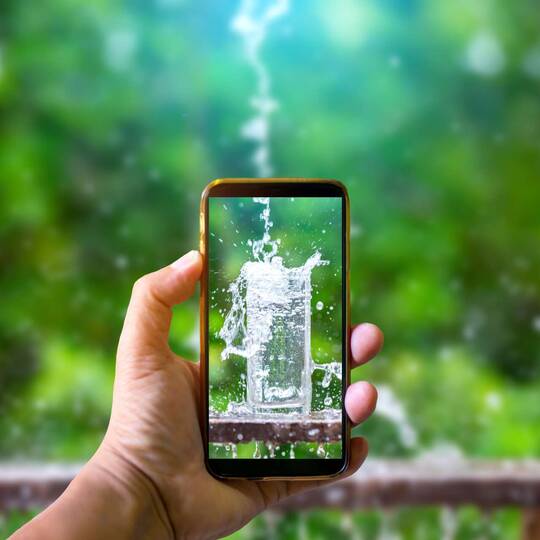Smartphone mit Wasserglas-Motiv hinter der Handykamera