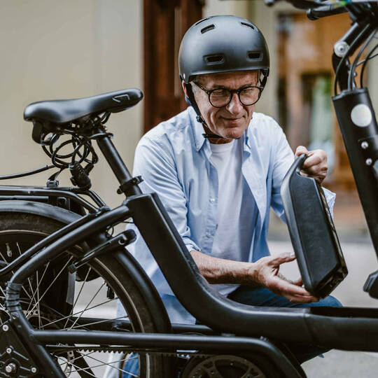 Mann in der Stadt nimmt Akku aus seinem E-Bike raus