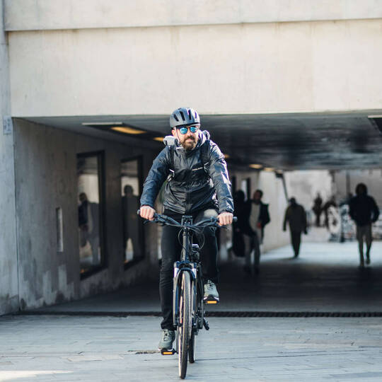 Mann mit Helm fährt mit E-Bike durch Stadt.