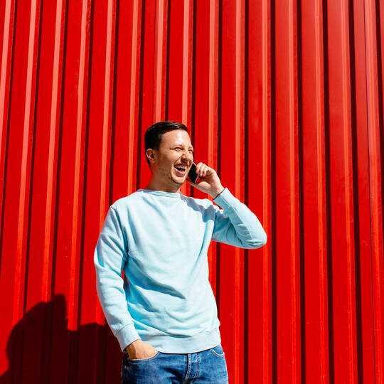 Mann telefoniert vor rotem Hintergrund