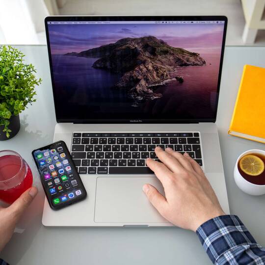 Schreibtisch mit MacBook, getränken, iPhone und Notizbuch