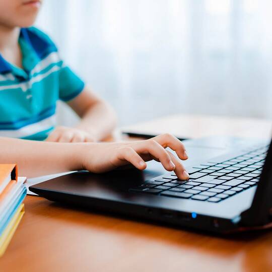 Kind sitzt am Laptop und lernt