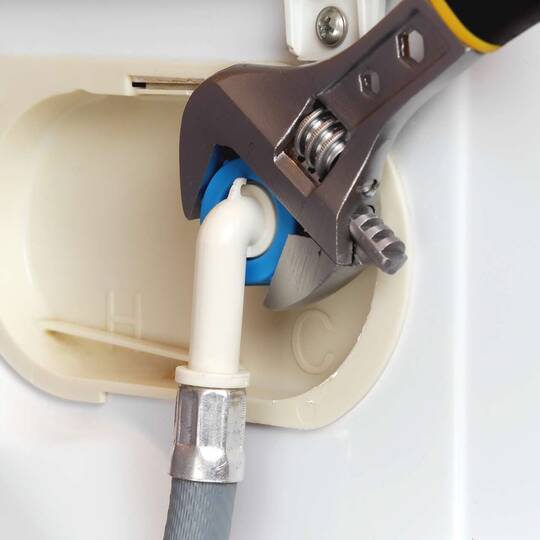 Wasseranschluss einer Waschmaschine wird mit einem Rollgabelschlüssel angezogen