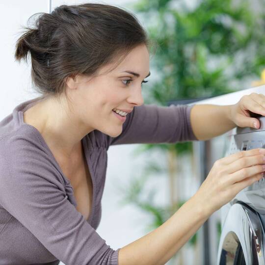 Eine Frau bedient eine Waschmaschine