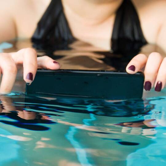 Frau im Wasser macht ein Foto mit ihrem Smartphone im Wasser.
