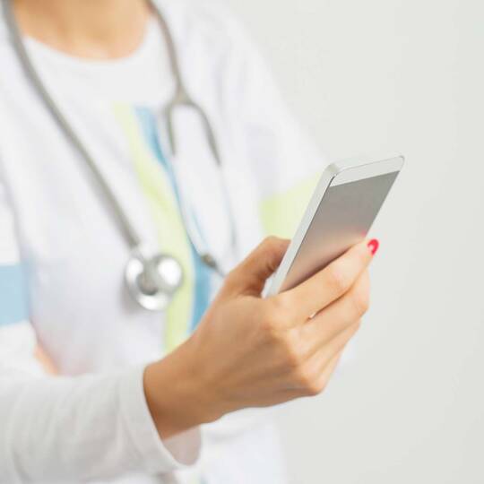 Eine Krankenhaus-Mitarbeiterin hält ein iPhone
