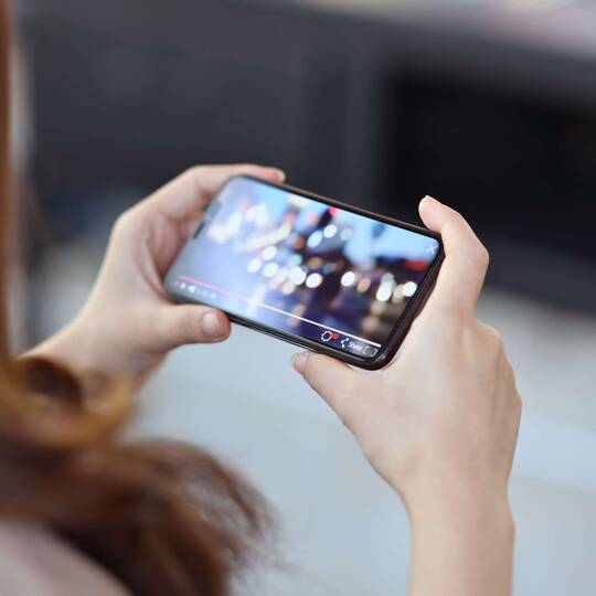 Eine Frau schaut auf dem Handy ein Video