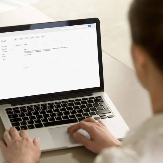 Frau sitzt vor Laptop mit geöffneter Gmail Anwendung